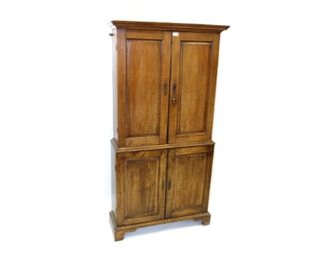 George III and later honey oak livery cabinet in two sections, each with adjustable shelves enclosed by fielded doors on brac