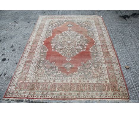 Large Eastern carpet with pale red ground centred by foliate pendant drop medallion conforming spandrels and multiple borders