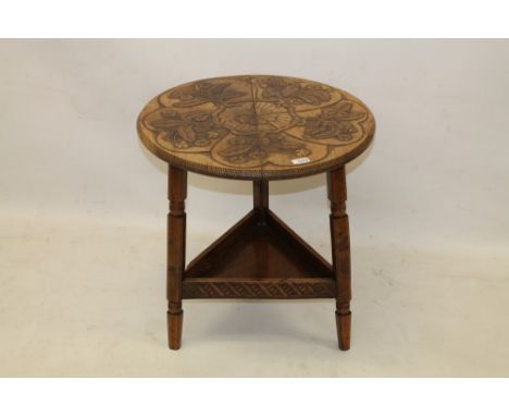 Late 19th / early 20th century carved pyrographed walnut cricket table in the Arts & Crafts style, circular top with relief f