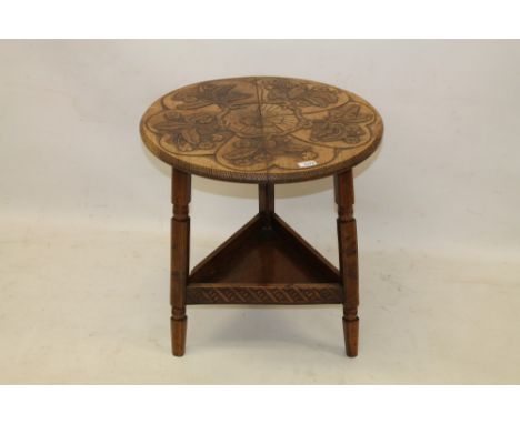 Late 19th / early 20th century carved pyrographed walnut cricket table in the Arts & Crafts style, circular top with relief f