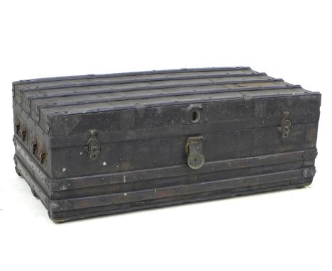 A late Victorian or Edwardian trunk, the wooden carcass bound in dark metal and wooden batons, with carrying handles to the s