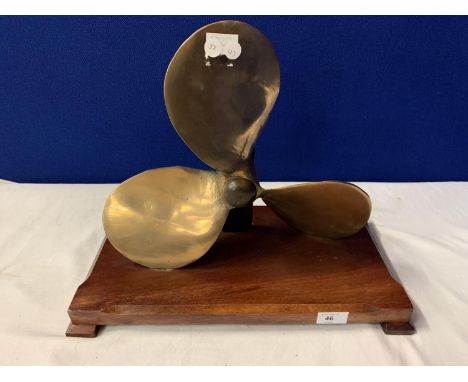 A VINTAGE BRASS PROPELLER MOUNTED ON A WOODEN BASE 