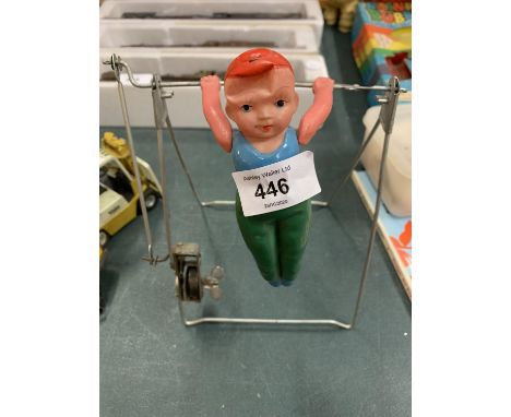 A VINTAGE WIND UP AND WEIGHED GYMNAST PERFORMING ON THE HIGH BAR 
