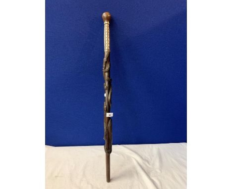 AN INTRICATELY CARVED WOODEN STICK WITH MOTHER OF PEARL STYLE DETAIL AND CROCODILE AND SNAKE DESIGN 