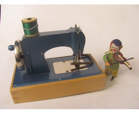 A vintage Schuco mechanical tin plate clockwork toy in the form of a clown playing the violin, along with a boxed child's sew