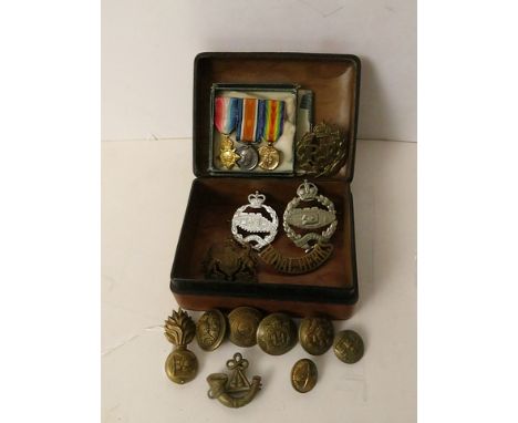 A small leather trinket containing cap badges, buttons and miniature medals