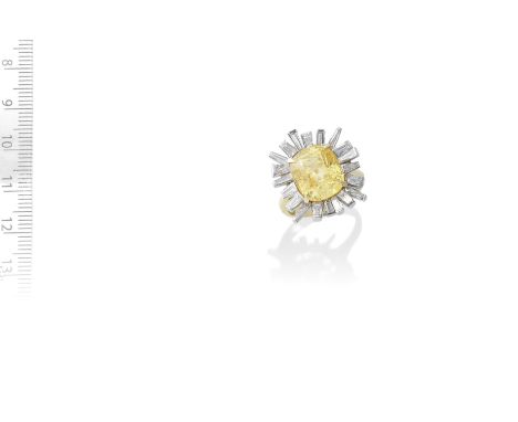 YELLOW SAPPHIRE AND DIAMOND RING, CIRCA 1970The cushion-shaped yellow sapphire, weighing 9.72 carats, within a surround of ta