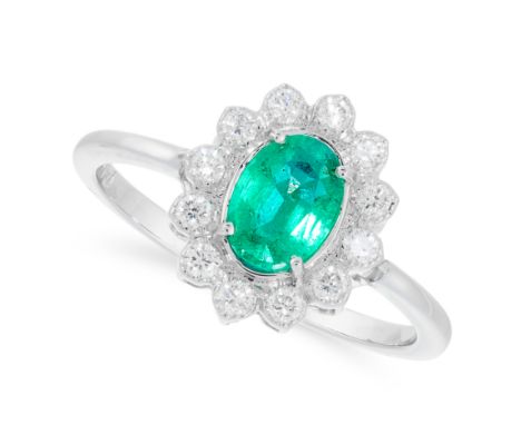 AN EMERALD AND DIAMOND CLUSTER RING in 18ct white gold, set with an oval cut emerald in a cluster of round cut diamonds, stam