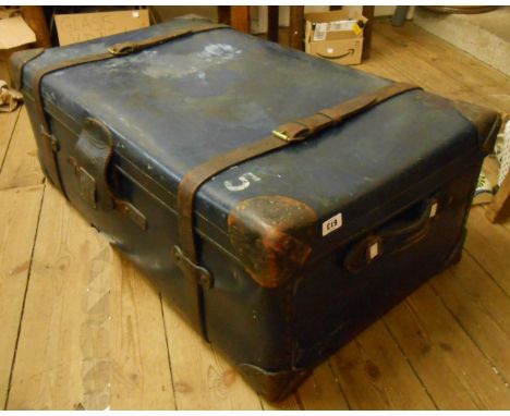 A large blue travelling trunk with leather straps, handles and corner reinforcements