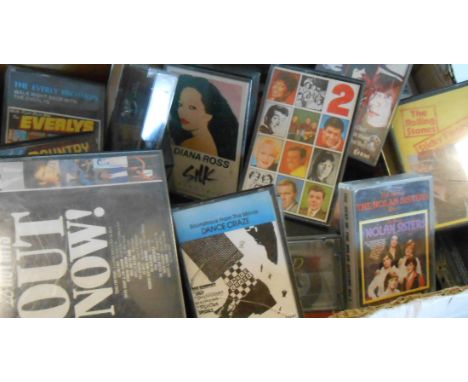 A box of assorted audio cassette tapes including Rolling Stones, Pointer Sisters, ABBA, etc.