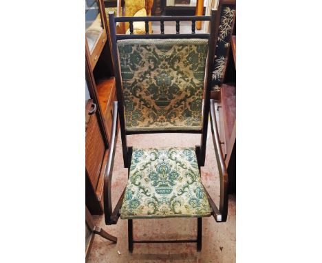 A late 19th Century stained wood campaign style folding elbow chair with spindle top rail and remains of tapestry upholstery