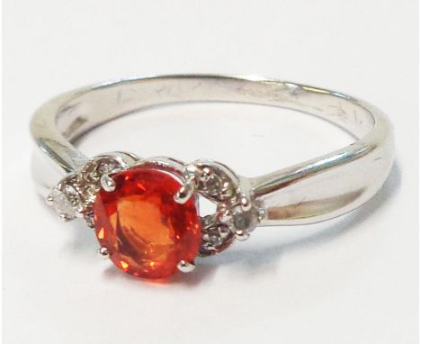 A 9ct. white gold ring, set with central orange sapphire and flanking tiny diamonds to shoulders