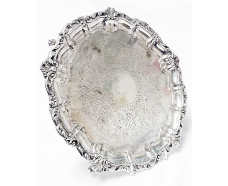 A 30cm diameter silver salver with decorative cast rim and engraving, set on claw and ball feet - Sheffield 1966