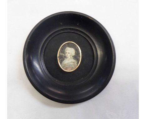 An ebonised framed and yellow metal bordered oval portrait miniature, depicting a 19th Century lady on a black background