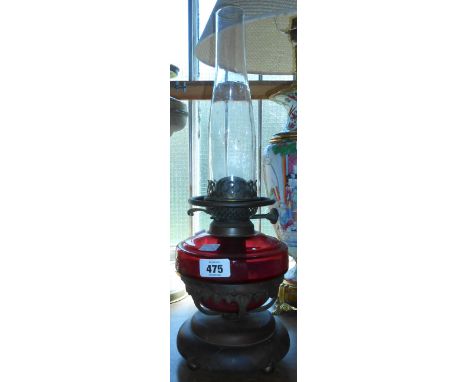 A table oil lamp with cranberry glass reservoir on bronzed cast iron base, with chimney