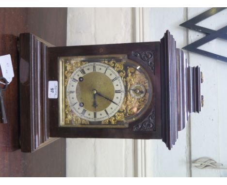 An Edwardian  mahogany mantel clock in the George III style, the caddy top with brass handle over an arched dial with gilt me