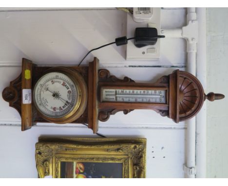 An Edwardian aneroid barometer with rosette and scroll carved frame and thermometer 59cm high