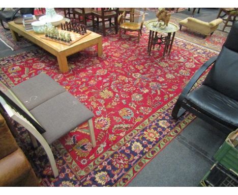 An Iranian Tabriz handwoven carpet with central red field decorated with floral embellishment, multiple borders, short tassel