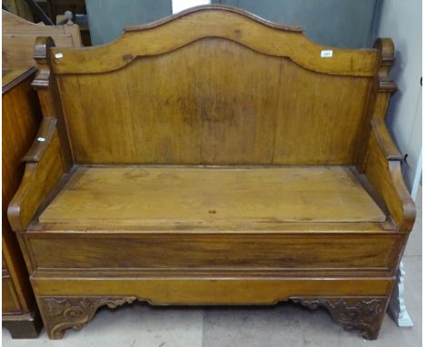 A 1920s carved and panelled oak hall bench, with rising lid, raised on acanthus leaf carved bracket feet, W124cm 