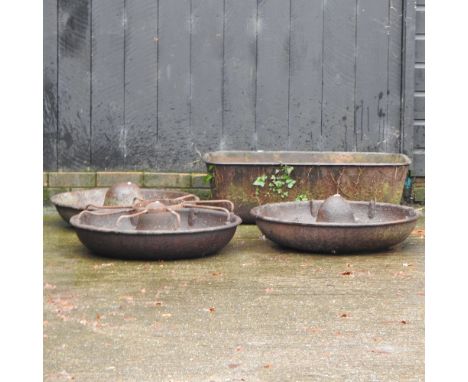 A large cast iron trough, 95cm wide, together with three circular cast iron pig feeders