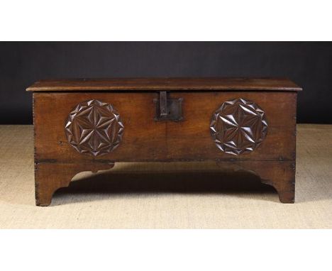 A 16th Century Boarded Oak Coffer.  The front board enriched with a pair of roundels chip carved with geometric flower heads 