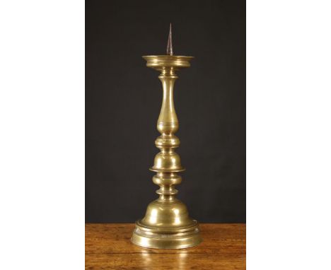 A Large 17th Century Pricket Stick. The iron spike centring a dished drip pan above a knopped baluster stem and bell form bas