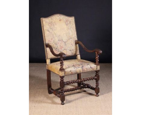 A 17th Century French Walnut Fauteuil. The arch topped rectangular back and seat re-covered in pale tapestry upholstery woven