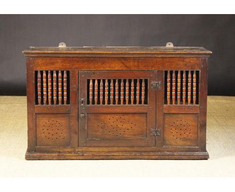 A 17th Century Oak Hanging Food Cupboard.  The central door hung on iron butterfly hinges and having a row of turned spindles