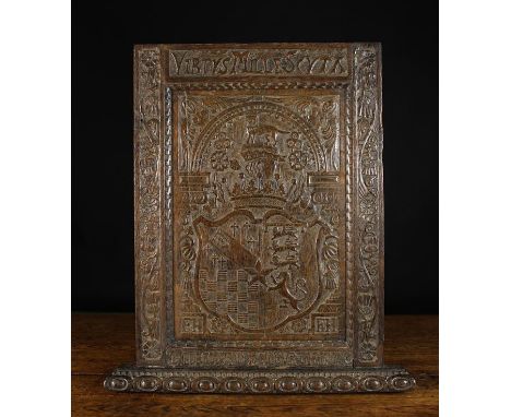 A Carved Oak Armorial Panel emblazoned with a heraldic shield surmounted by a lion, helm and crown, beneath a scallop edged a