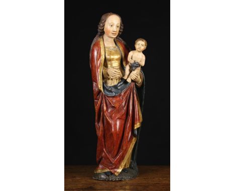 A 15th Century German Polychromed Caving of Madonna & Child. The Virgin depicted with long brown hair flowing over a red drap