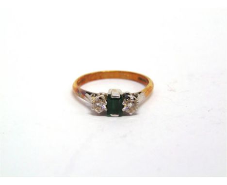 AN EMERALD AND DIAMOND THREE STONE RING stamped '18ct', the small step cut stone flanked either side by a brilliant cut, tota