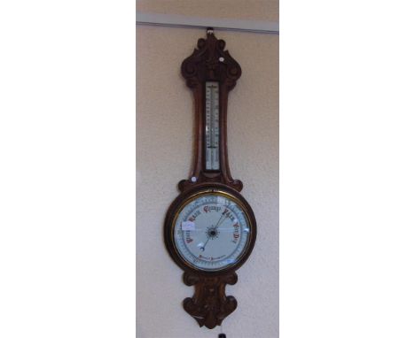 AN EDWARDIAN CARVED OAK ANEROID BAROMETER/THERMOMETER, with ceramic dial, 83cm high; together with another room thermometer w