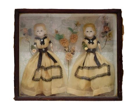 19th Century doll's diorama set with two porcelain headed dolls with wooden lower limbs in fine gauze dresses with black sash
