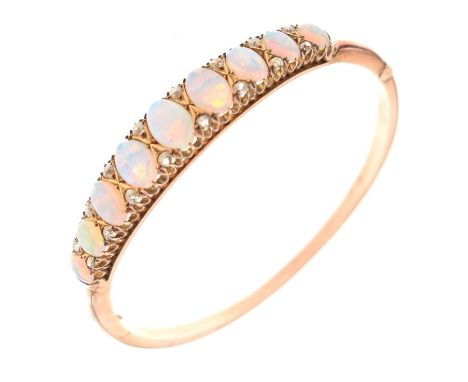 Edwardian opal and diamond hinged bangle, in unmarked yellow gold, the nine oval graduated cabochons with pairs of old Swiss 