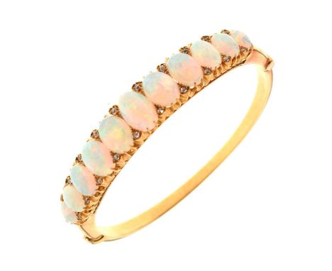 Edwardian opal and diamond hinged bangle, in unmarked yellow gold, the eleven oval graduated cabochons with pairs of old Swis