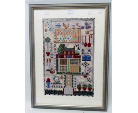 A framed modern woolwork sampler style panel with central cottage within kitchen themed border