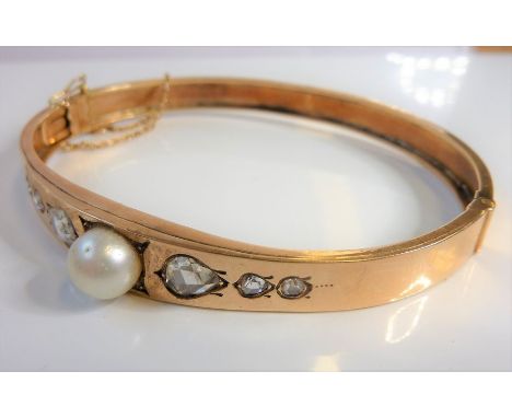 A 19th century rose-gold coloured bangle, centrally set with a pearl flanked each side by three graduated diamonds (total wei