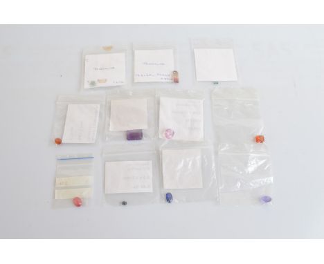 A collection of loose various gemstones, including tourmaline, garnet, sapphire, amethyst, kyanite, ruby, kunzite and two oth