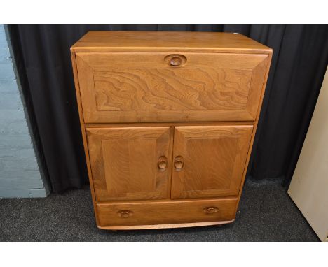 An Ercol fall front oak cabinet, having fitted interior with cupboard under and frieze plinth drawer, 83cm wide x 43cm x 111c