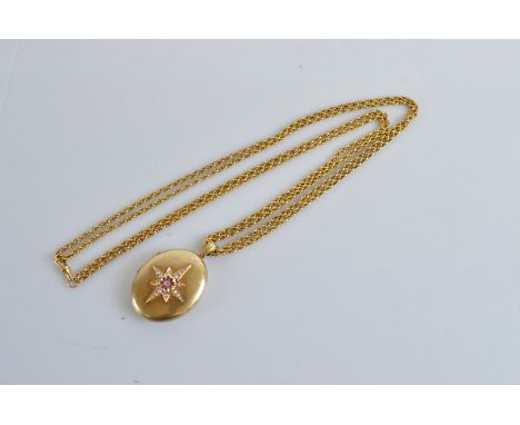 A Victorian oval yellow metal locket and chain, the locket centred with seed pearl, diamond and ruby star, the reverse with e