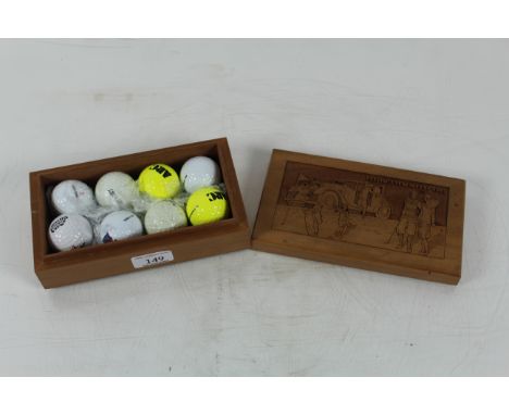 A vintage wooden presentation box containing eight unused golf balls, the lid well carved with images of golfers and veteran 