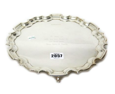 A silver salver, of shaped circular form, in the Chippendale style, with a pie-crust rim, raised on three scrolling feet, dia