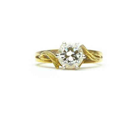 A gold and diamond set single stone ring, claw set with a circular cut diamond, between rustically decorated crossover should