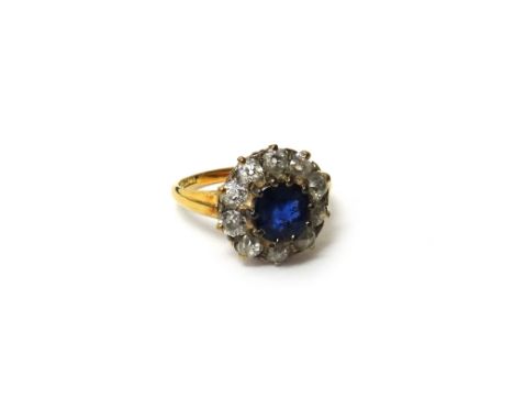 A gold, sapphire and diamond set cluster ring, claw set with the cushion shaped sapphire at the centre, within a surround of 