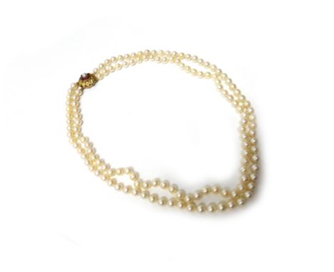 A two row necklace of uniform cultured pearls, on a gold, ruby and cultured pearl set clasp, designed as a flowerhead, length
