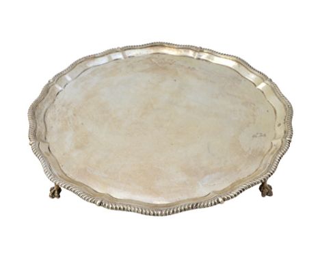 A silver salver, of shaped circular form, in the Chippendale style, the pie-crust rim with gadrooned decoration, raised on fo