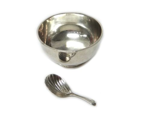 Silver, comprising; a circular plain sugar bowl, on a circular foot, London 1957 and a George III caddy spoon, the bowl of sc