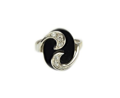 A white gold, diamond and black onyx ring, the oval black onyx with two diamond set three stone crescent shaped motifs above,