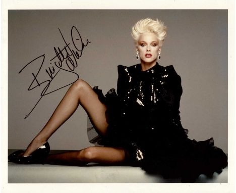 NIELSEN BRIGITTE: (1963- ) Danish actress and model. Signed colour 10 x 8 photograph of Nielsen seated in a glamorous full-le
