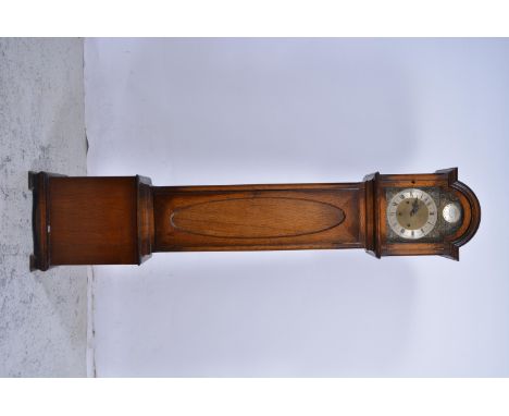 An oak reproduction longcase grandmother clock, the 22cm dial having a roman numeral chapter ring and arched hood, panelled d